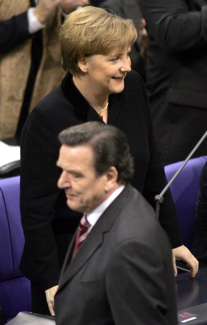2005年11月22日，即将离任的德国总理施罗德（下）在向新当选的德国总理默克尔（上）表达祝贺后离开。当日，51岁的默克尔在联邦议院投票表决中当选新一届联邦总理。她也是德国历史上第一位女总理。