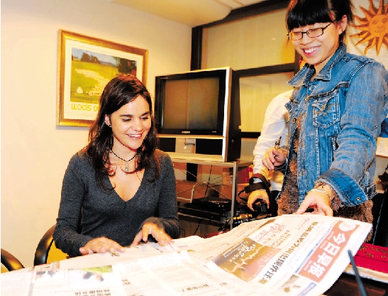 昨日，在乌拉圭驻上海总领馆，玛丽亚在看杭州媒体有关她西湖救人的报道。  记者 胡元勇 摄