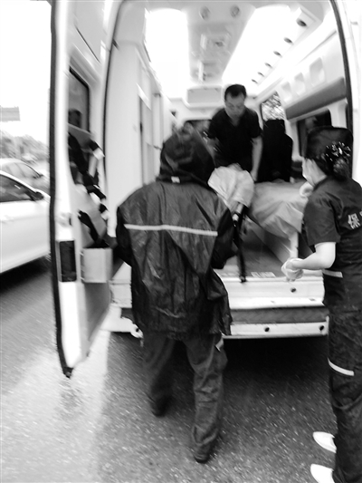 冒雨把患者抬上救护车。