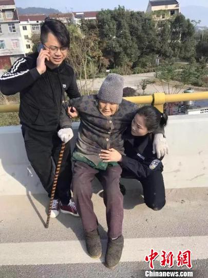 图为：一女警察跪地用身体为老太太支起“暖椅”。台州公安供图