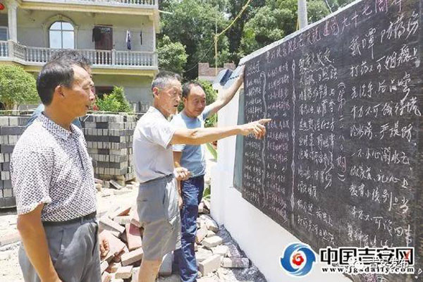 胡仁生（中）在编好的黑板报前与村民交流