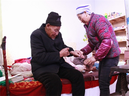标题图：李桂英为98岁高龄的公公整理衣服。.jpg