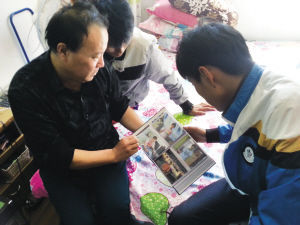 赵君路在翻阅他资助、收养过的少年照片